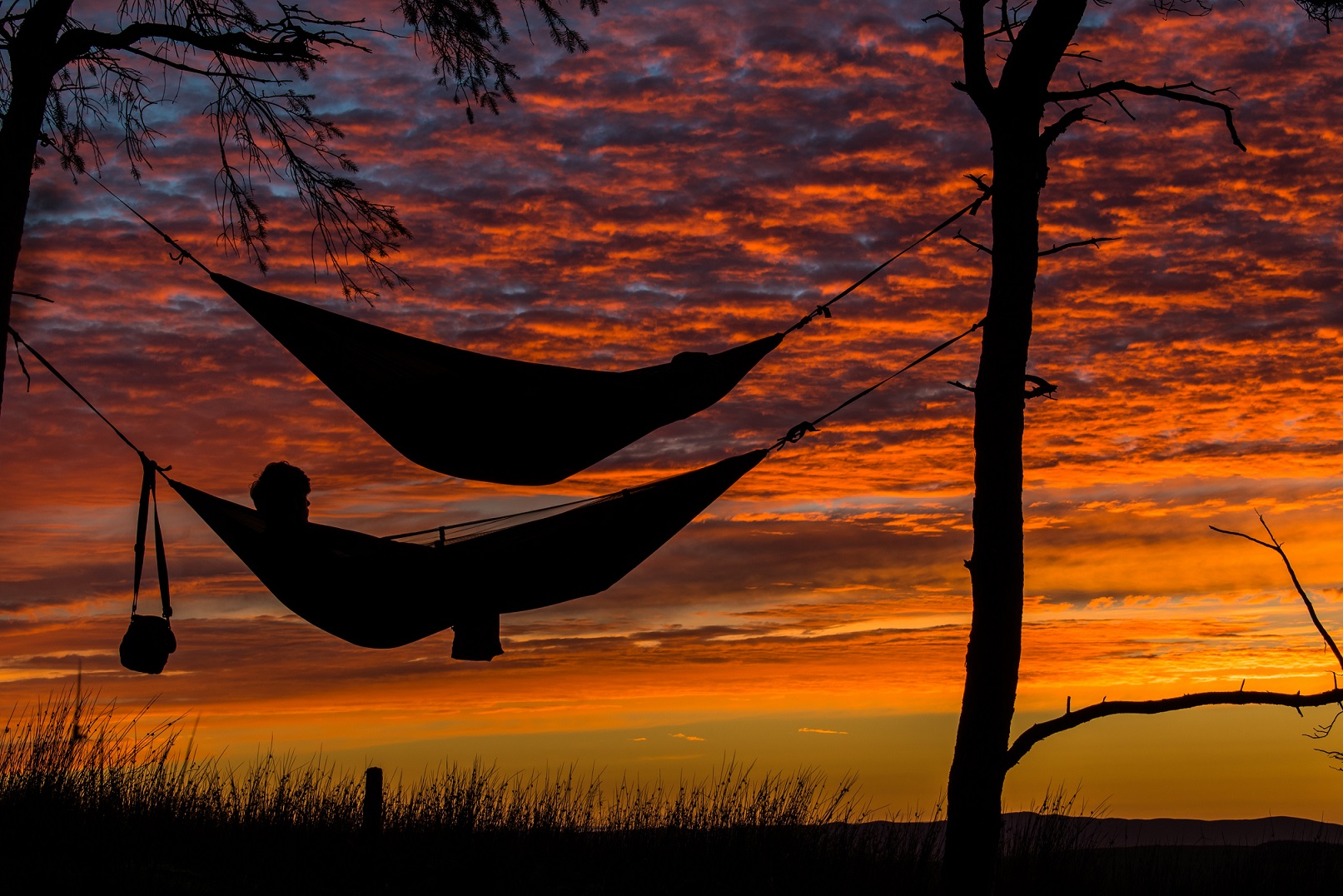 Ein Minijobber genießt seinen Mindesturlaub in einer Hängematte bei Sonnenuntergang